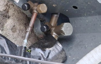 Pipes and fittings of a mechanical system with visible bolts and some tape on a surface.