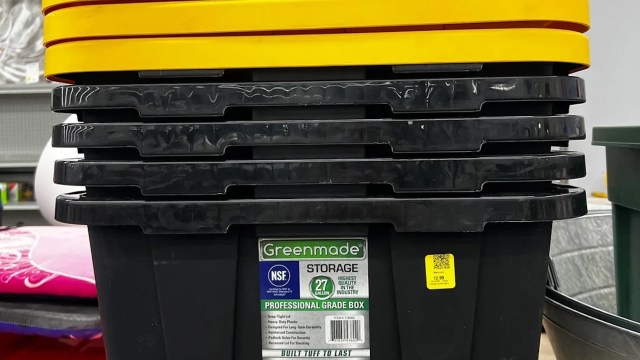 A stack of black storage bins with a yellow lid on top, labeled as professional grade.