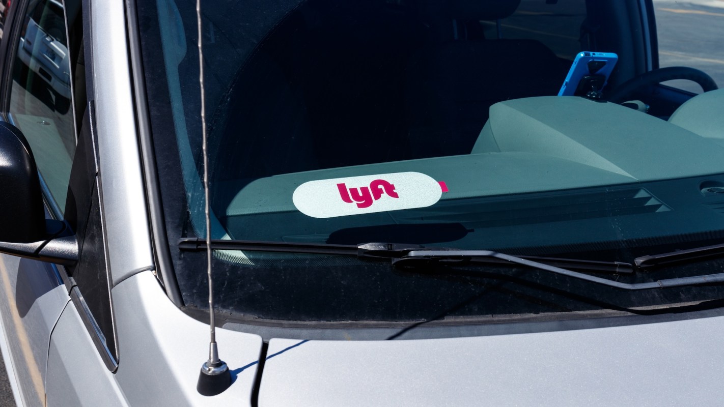 A Lyft sticker displayed on the windshield of a silver vehicle.