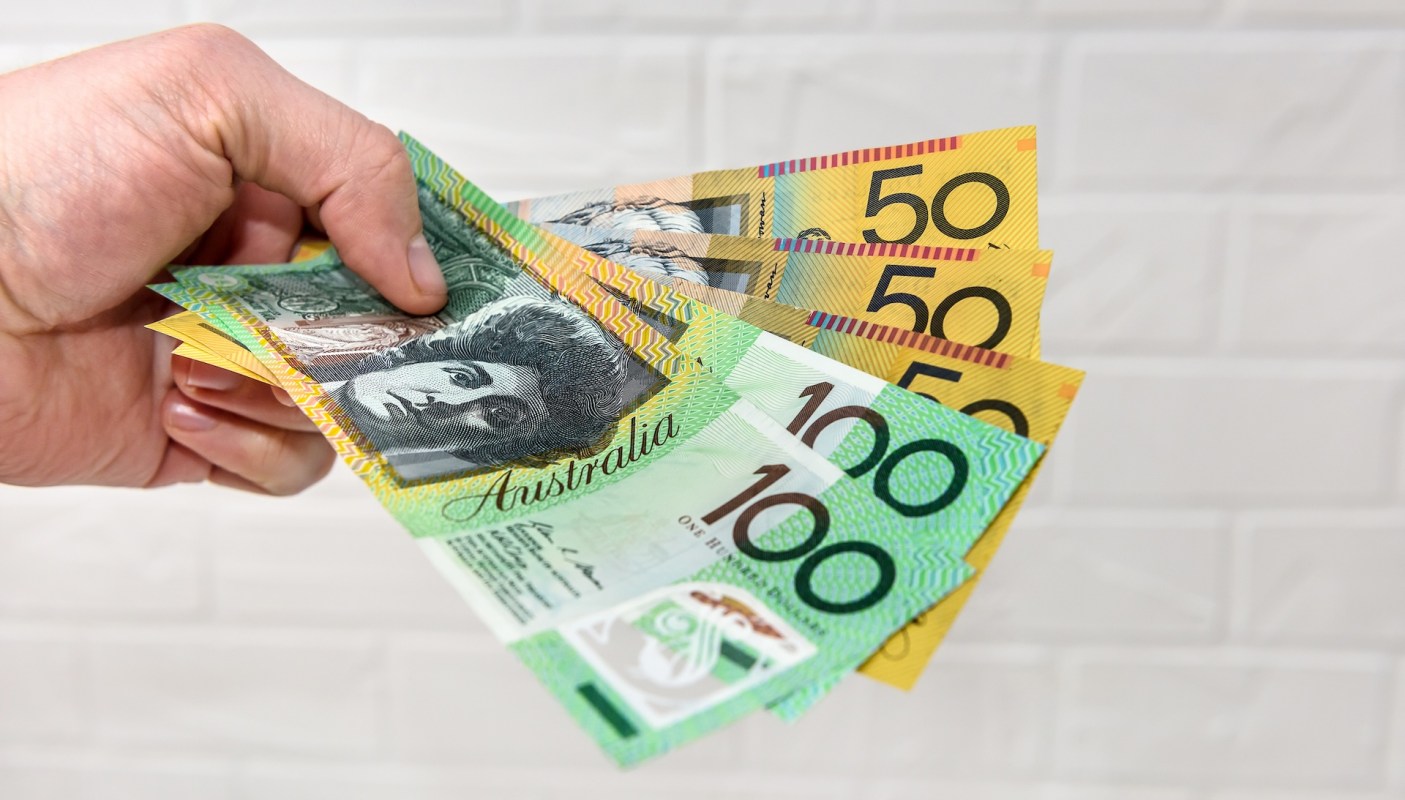 A hand holding Australian banknotes.