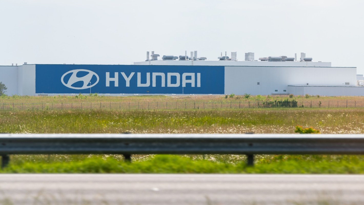 A large Hyundai manufacturing facility is visible behind grassy land.