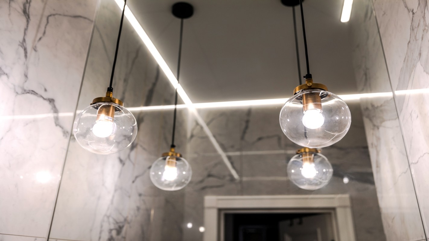 Three pendant lights hang from the ceiling in an interior space with marble walls.