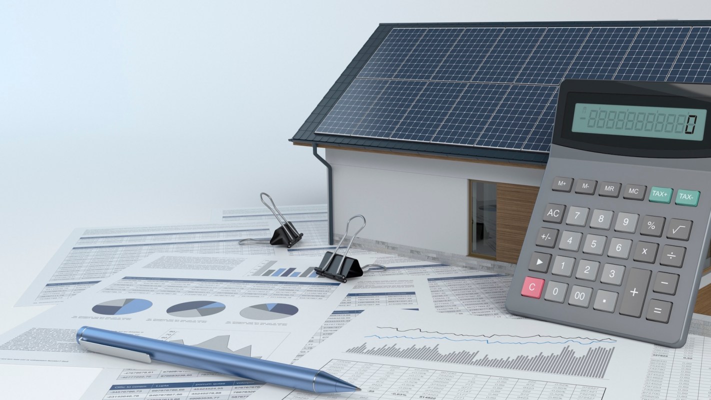 A house with solar panels surrounded by financial documents and a calculator.