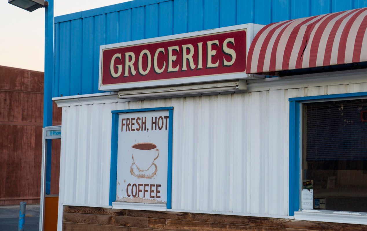 A grocery store exterior with a sign advertising fresh hot coffee.