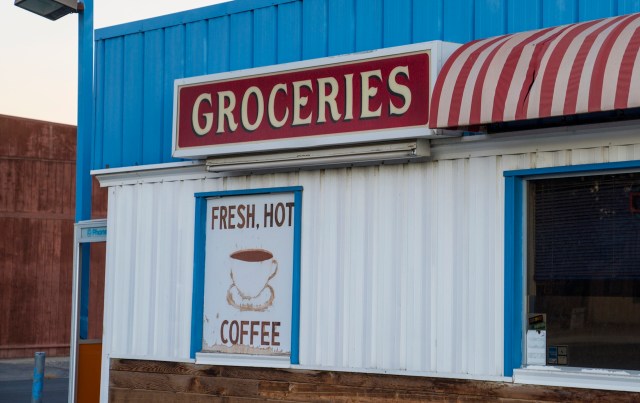 A grocery store exterior with a sign advertising fresh hot coffee.