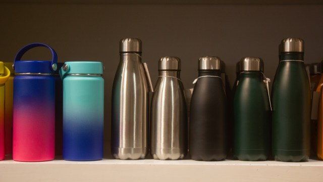 A row of various water bottles in different colors and styles on a shelf.