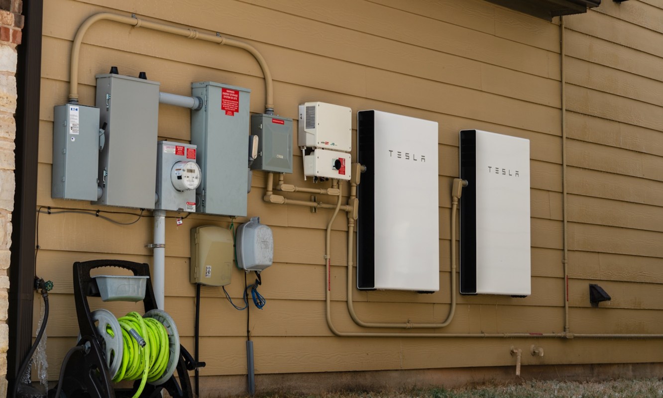 Electrical equipment, including Tesla batteries and utility meters, mounted on a wall.