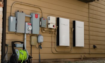 Electrical equipment, including Tesla batteries and utility meters, mounted on a wall.