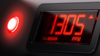 A digital CO2 sensor displaying a level of 1305 PPM with a red indicator light.