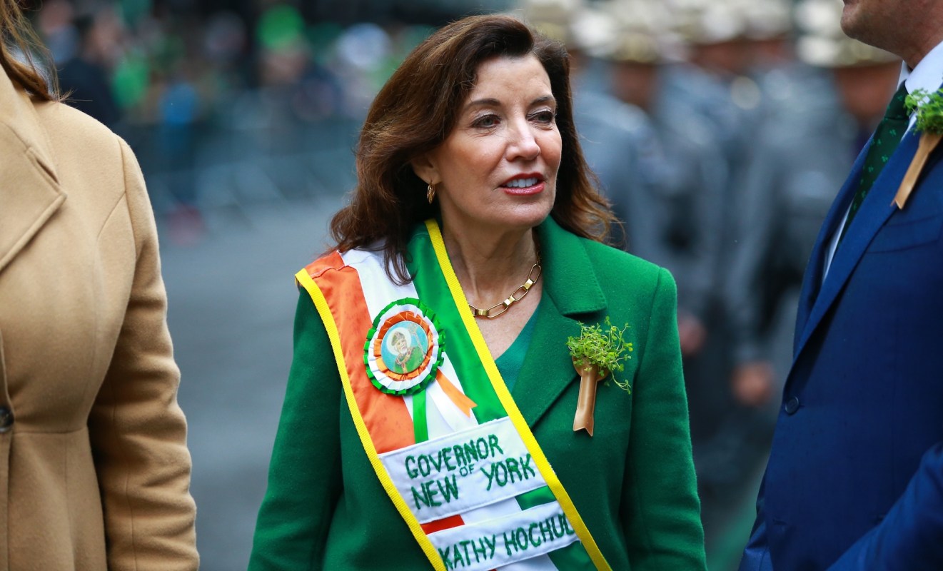 New York Governor Kathy Hochul wearing a green coat and sash at a parade.