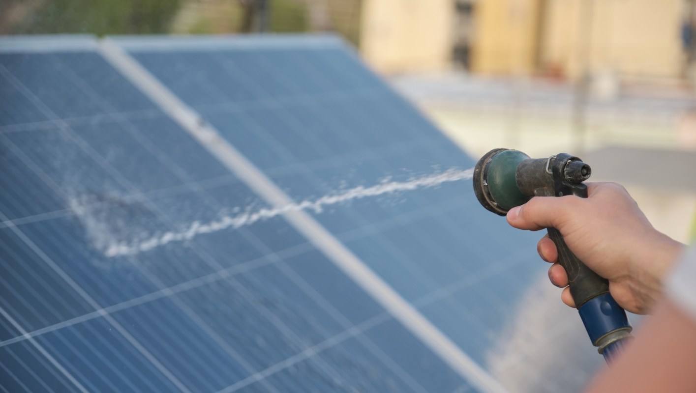 A person sprays water on solar panels.