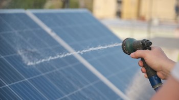 A person sprays water on solar panels.