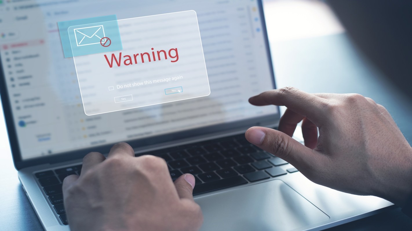 A person interacting with a laptop displaying a warning message about email.