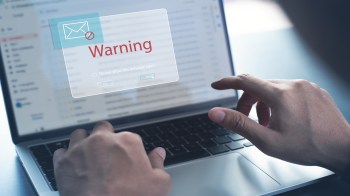 A person interacting with a laptop displaying a warning message about email.