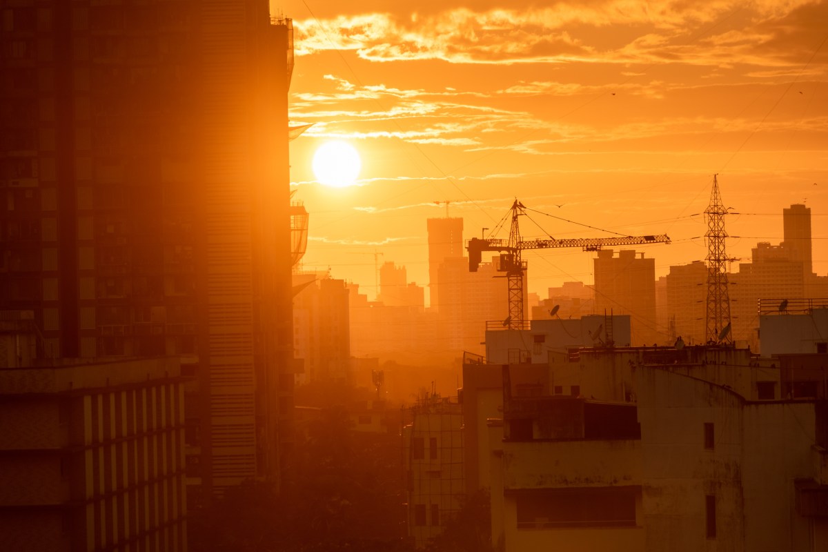 Mumbai, India - September 2022: Silhouette of a construction crane on a building at sunset with a skyline of the suburb of Kandivali in the background.