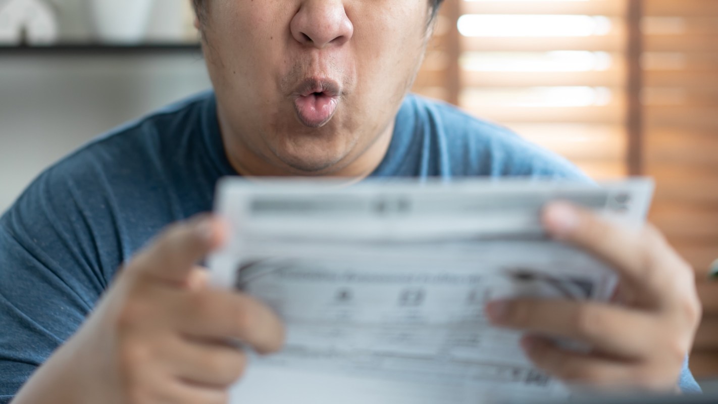 A man holds a piece of paper with a surprised expression.