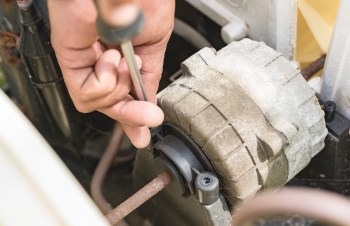 A person using a screwdriver to work on a mechanical component.