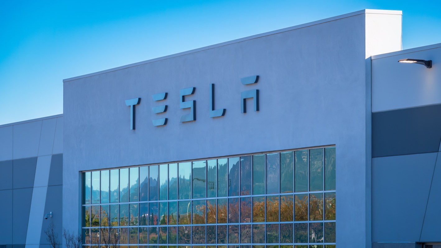 The exterior of a building with the Tesla logo and large reflective windows.