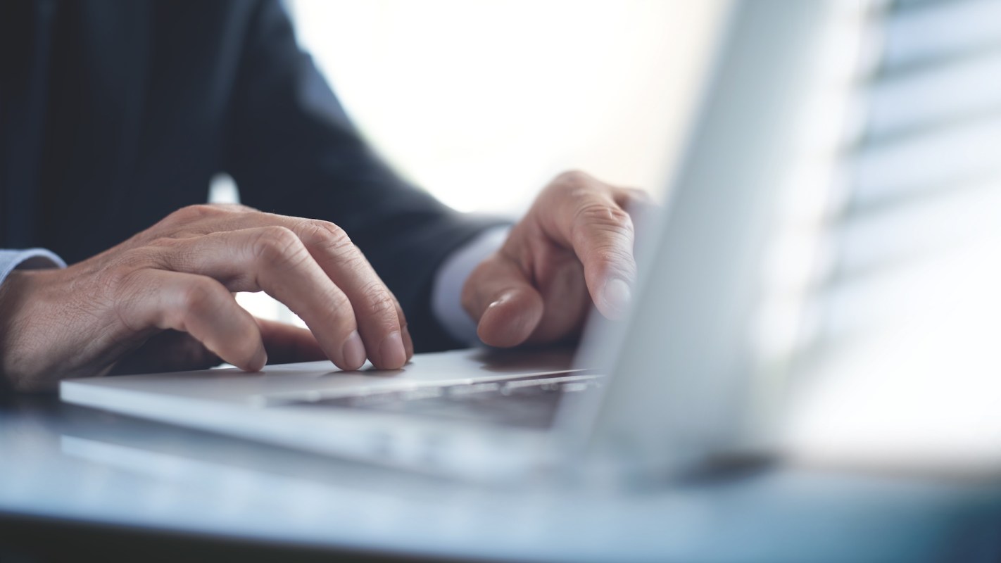 A person types on a laptop keyboard.
