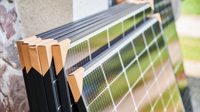 Stacked solar panels secured with cardboard packaging.