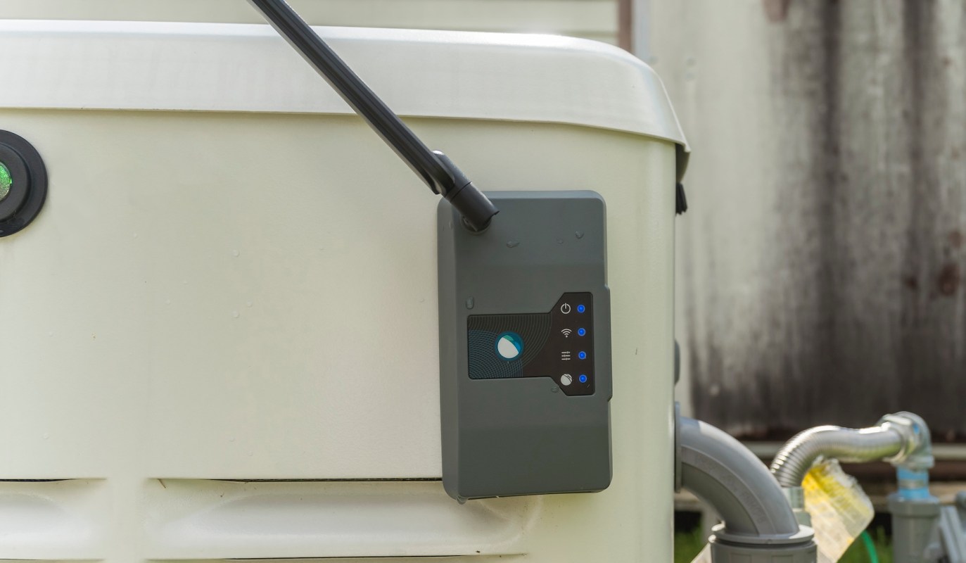 A smart device mounted on a standby generator with LED indicators and a connection hose.