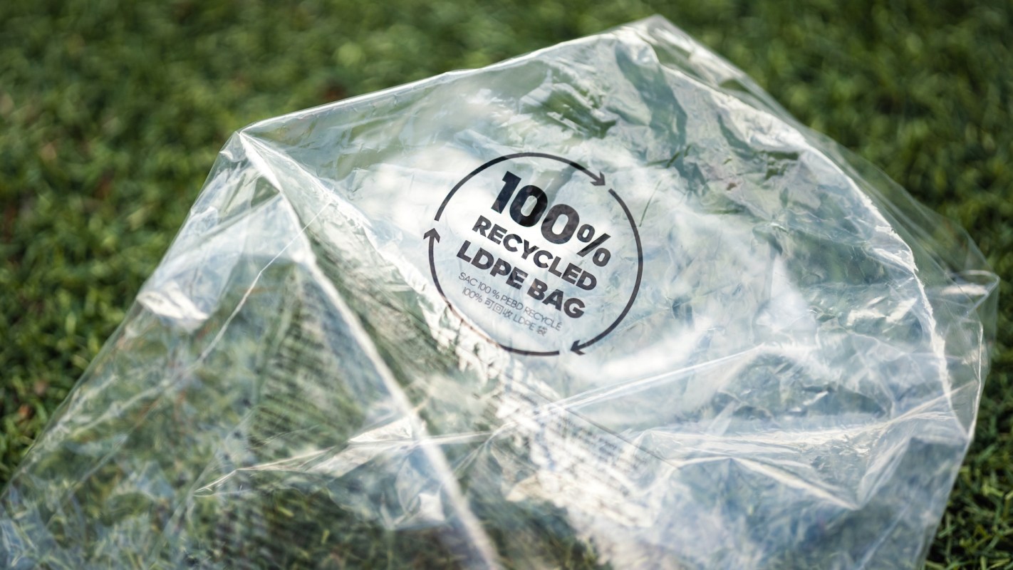 A clear plastic bag labeled "100% recycled LDPE bag" on green grass.
