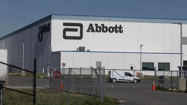 A large industrial building with the "Abbott" logo, surrounded by a fence and parking area.