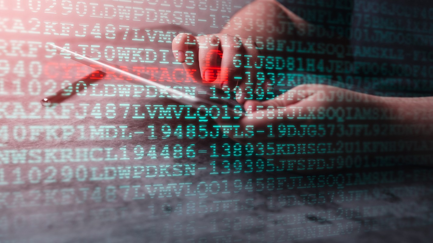 A hand holds a smartphone with digital code displayed in the background.