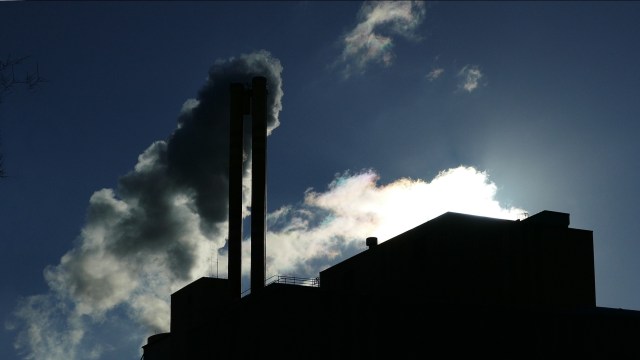 A silhouette of factory smokestacks against a cloudy sky.