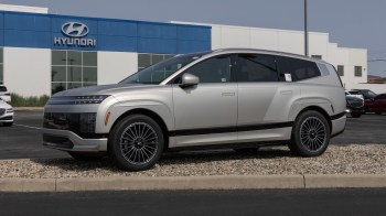 A silver Ioniq 9 SUV parked in front of a Hyundai dealership.
