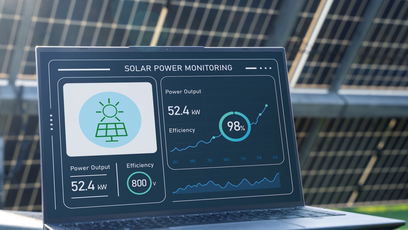 A laptop displaying solar power monitoring data including power output and efficiency statistics.
