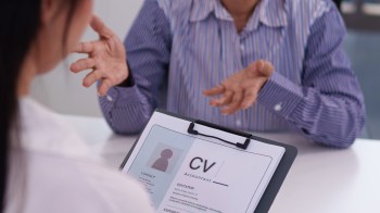 A person discusses a CV during a job interview at a table.