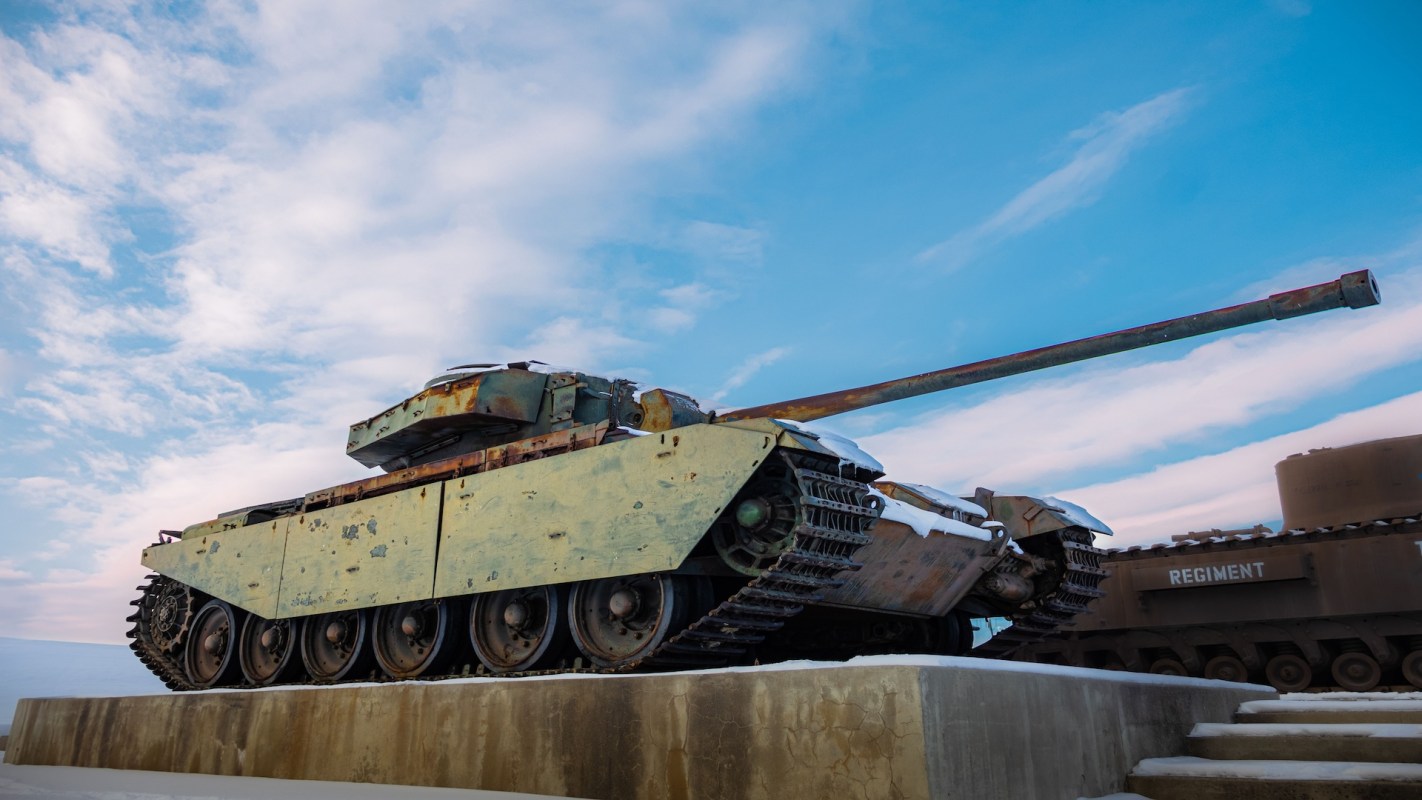 A military tank displayed on a platform with a snowy background and blue sky.