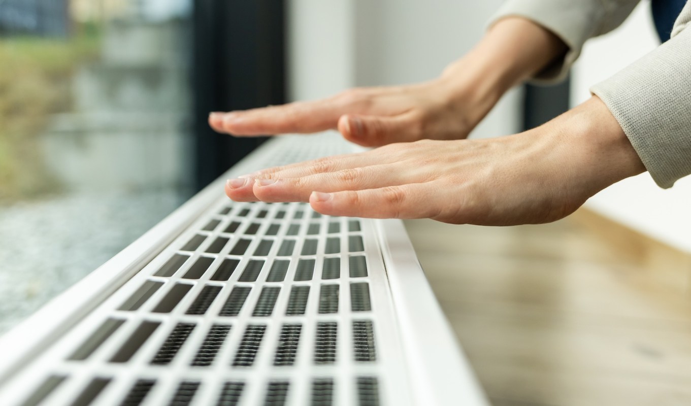 A person places hands over a vent in a modern interior space.