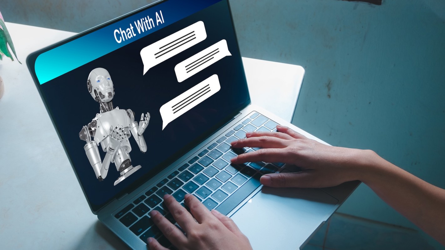 A person types on a laptop displaying a chatbot interaction.