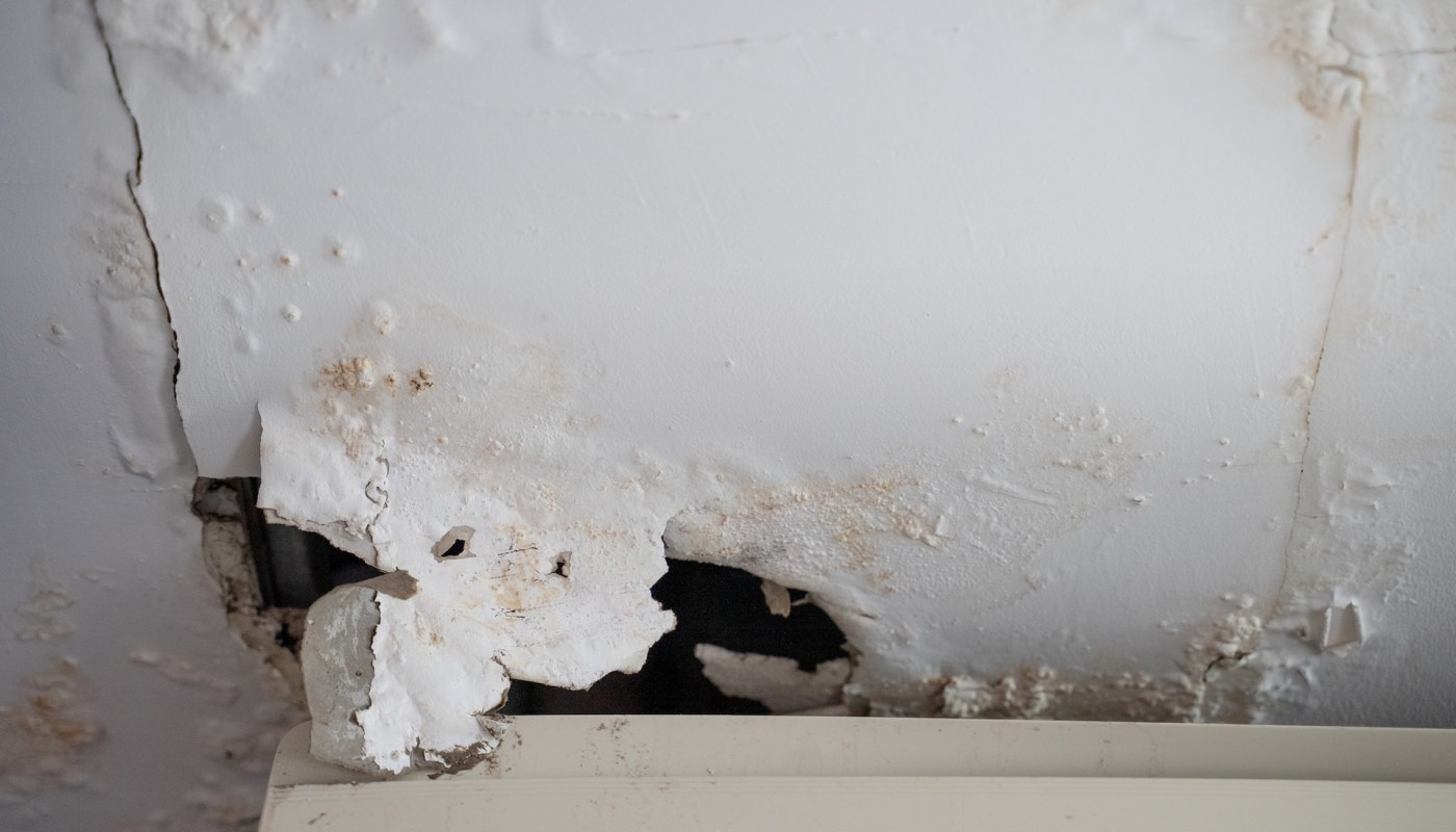 Damage and peeling paint on a white wall, with visible discoloration and deterioration.