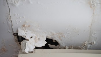 Damage and peeling paint on a white wall, with visible discoloration and deterioration.
