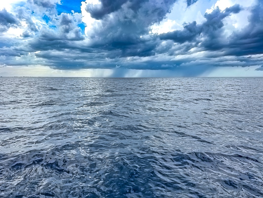 A view of the ocean under a cloudy sky with varying shades of blue and gray.