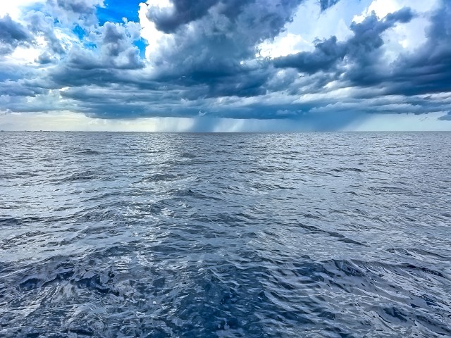 A view of the ocean under a cloudy sky with varying shades of blue and gray.