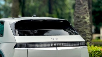 A Hyundai Ioniq 5 parked in a green area with trees and shrubs in the background.