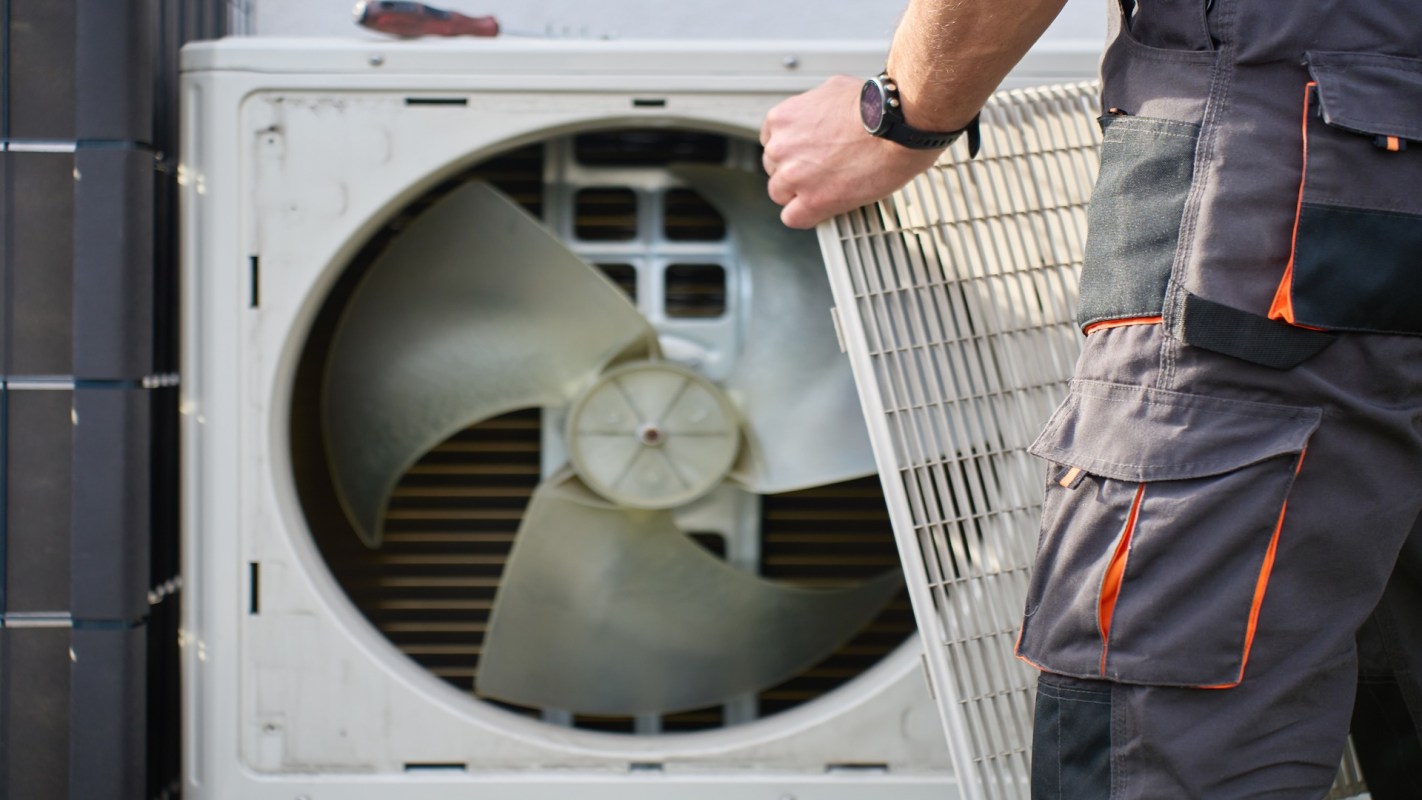 A technician removes the cover from an outdoor air conditioning unit.