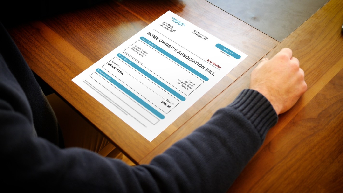A hand rests on a wooden table beside a homeowners association bill.