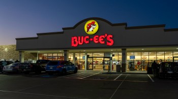 A Buc-ee's convenience store with bright signage and parked cars at dusk.