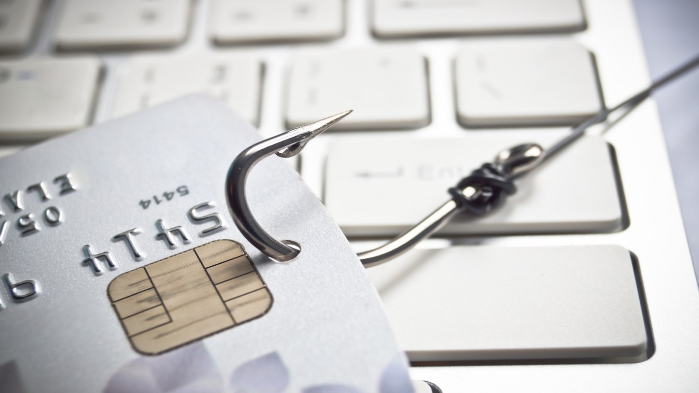 A fishing hook looped into a credit card on a computer keyboard.