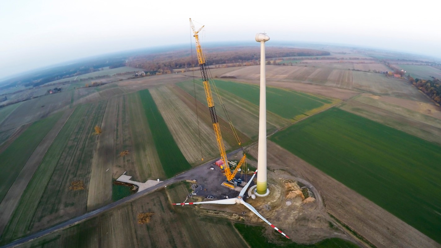 A crane assists in constructing a wind turbine.