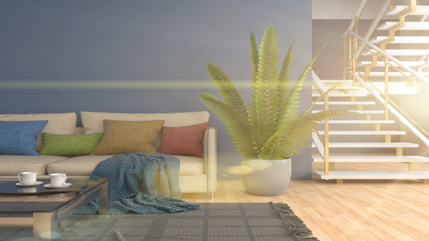A cozy living room with a sofa, colorful cushions, a coffee table, and a potted plant near a staircase.
