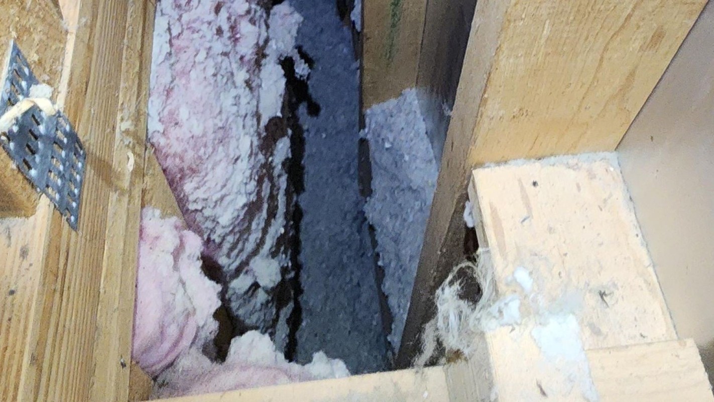 An insulated gap between wooden beams filled with pink insulation material.