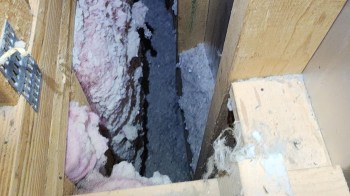 An insulated gap between wooden beams filled with pink insulation material.