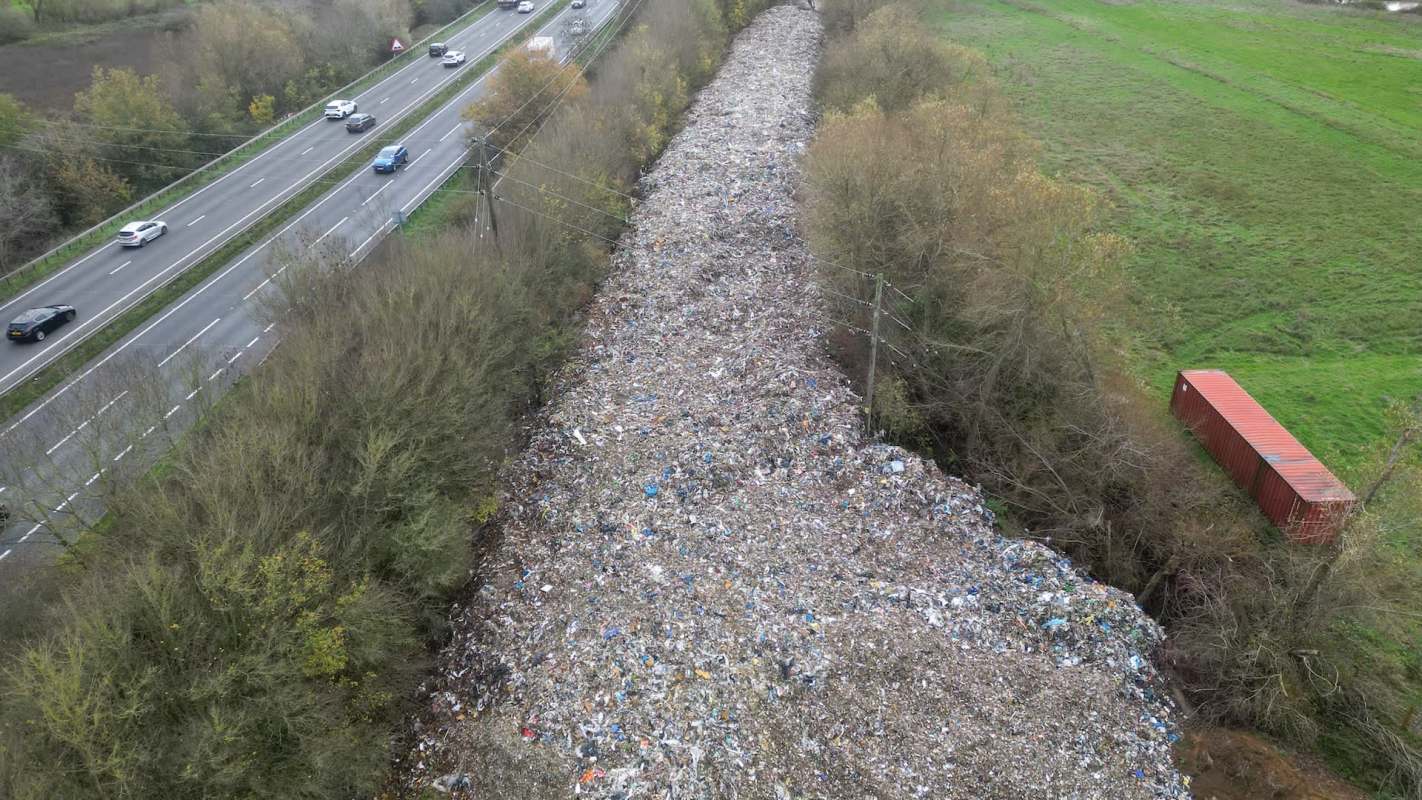 A large pile of waste near a highway and river.