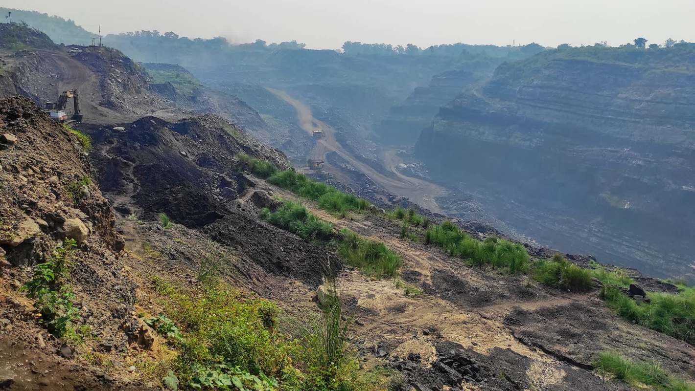 A large open-pit mining area with steep, rocky slopes and a dirt road running through it.